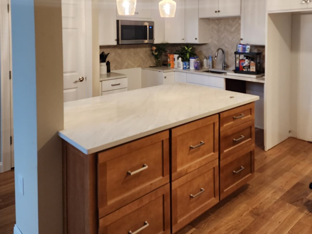 Remodeled kitchen with white cabinets, a wood island and a stone countertop