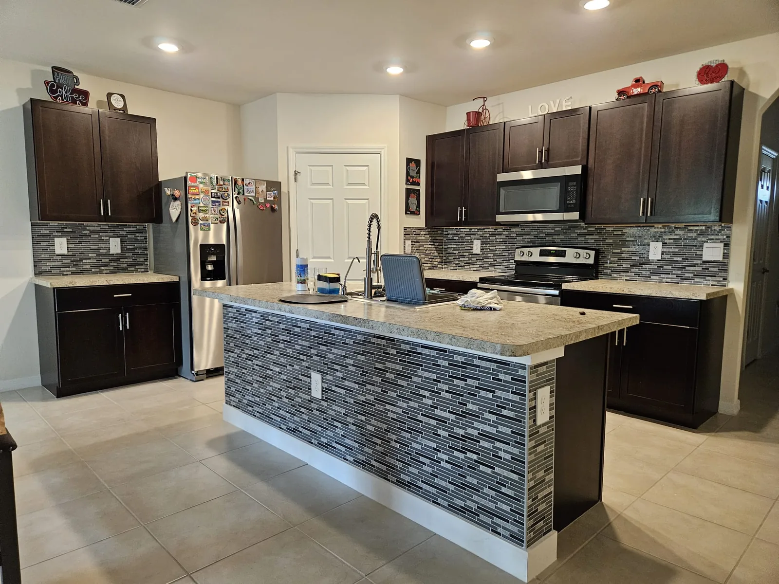 Kitchen with dark cabinets, tile backsplash and a tiled island