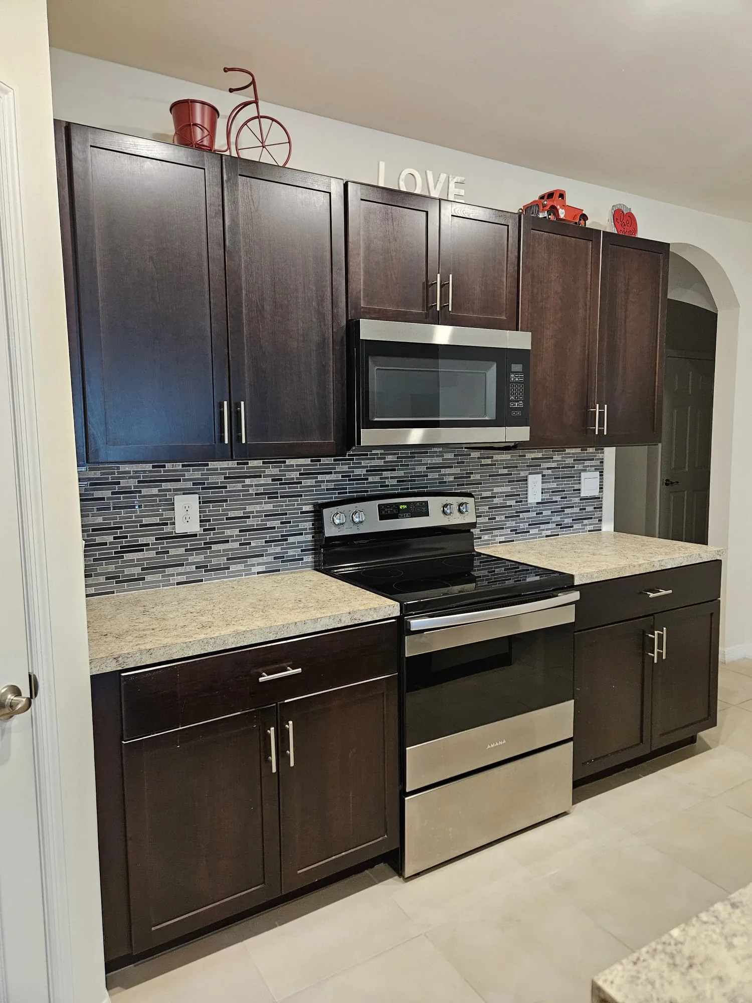 Dark kitchen cabinets with mosaic tile backsplash around the range