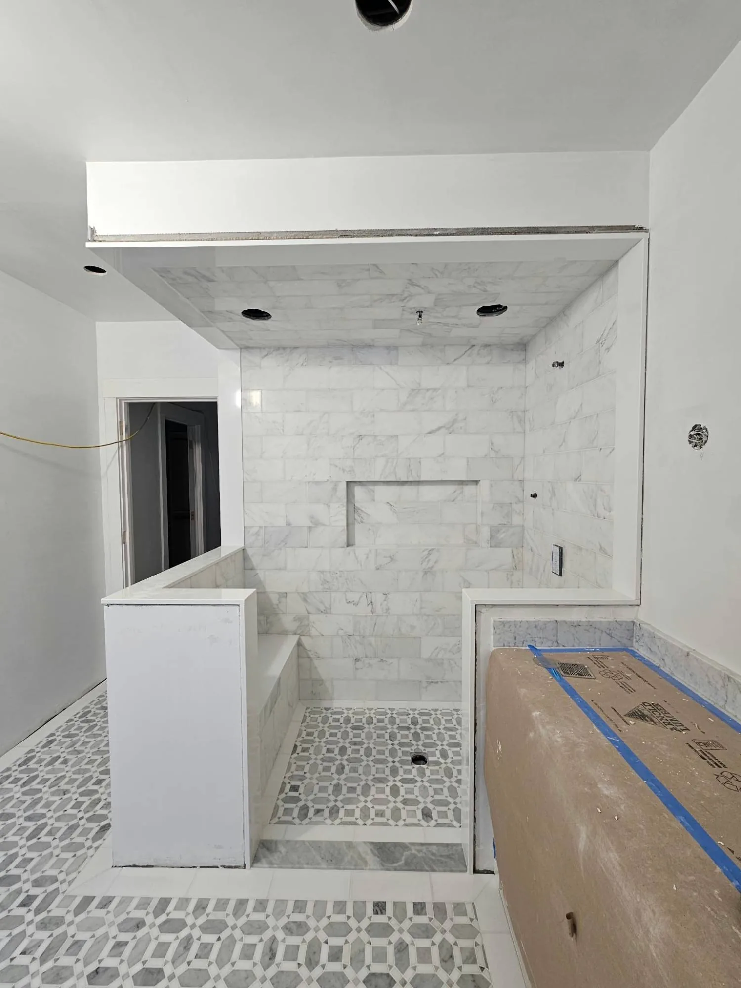 Walk-in shower with marble wall tile, a tiled bench and mosaic floor