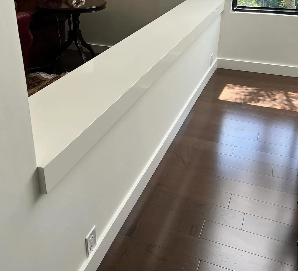 Dark hardwood floor with white baseboard and a finished half wall